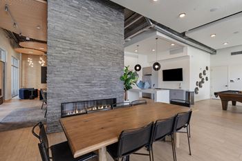 A modern dining room with a stone fireplace and wooden table.